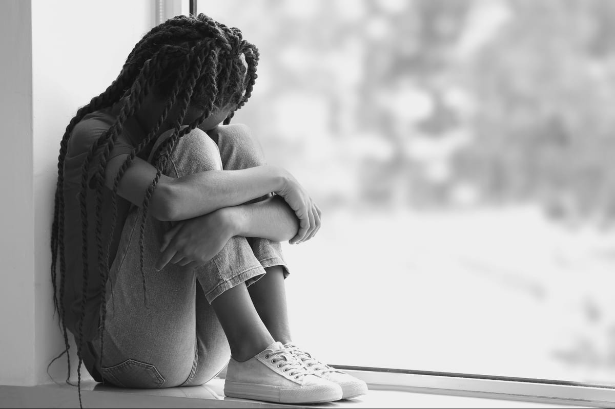 A child sitting alone at a window
